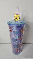 Full view of tumbler showing Pooh topper, lid, straw, and character graphics