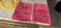 Pair of bright pink shag bath mats laid flat showing color and texture