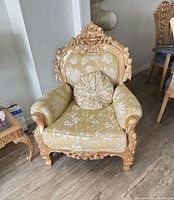 Front view of ornate carved solid wood sofa with yellow floral upholstery and round pillow