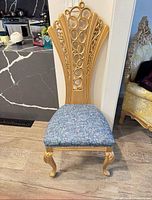 Front view of ornate gold dining chair with blue floral seat