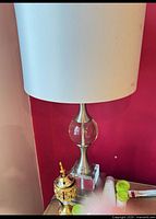 One of the crystal and metal table lamps with white drum shade shown on tabletop