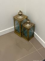 Two gold-tone lanterns of different heights with blue LED lights inside