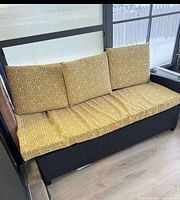 black rattan bench with yellow geometric cushions