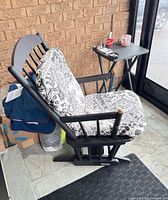 Overall view of black wood glider rocking chair with patterned cushions