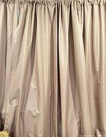 Front view of beige room-darkening curtain panels hanging, showing texture and color