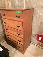 Front view of wood highboy showing five drawers and hardware