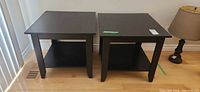 pair of dark wood veneer side tables front view