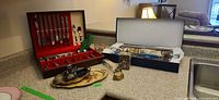 overview of lot on countertop showing flatware box, blue tray box, trays, bell, scoop, mini stein