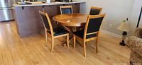 Round wood dining table with four matching chairs, front view
