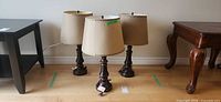 Front view of three matching table lamps with shades on floor