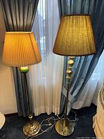 Both brass floor lamps with shades displayed side by side