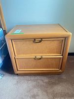 Front view of one oak nightstand showing two drawers and pulls