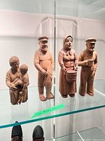 Front view of all four wooden figurines on glass shelf