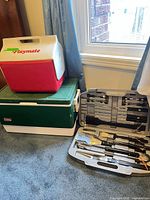 Coleman chest cooler, Igloo Playmate cooler stacked, BBQ tool set open showing contents
