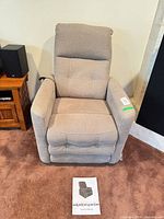 Front view of beige power recliner with manual on floor