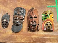 All four wooden face plaques displayed side by side on table surface