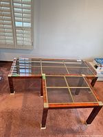 Coffee table and end table showing glass tops, wood veneer frames and brass trim
