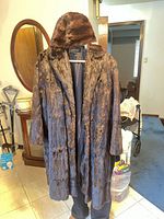Full view of mink fur coat on hanger with hat displayed over collar