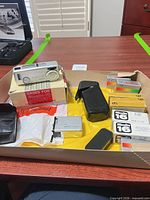 Tray with camera, cases, film boxes, flashbulbs, original carton