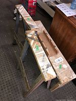 Two paint-splattered folding sawhorses side by side