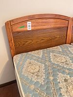Wooden headboard with mattress on metal frame, showing finish and fabric pattern