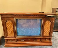 Front view of Zenith console TV showing wood cabinet, screen and decorative drawers