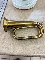Side view of brass bugle horn showing full length and mouthpiece