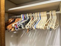 Full closet rod showing majority of light wood and plastic hangers