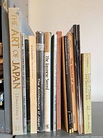 Group of 13 Japanese art reference books standing on shelf with spines visible