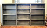Front view showing all three blue-grey metal bookcases side by side
