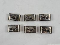 Six silver plated rectangular napkin rings with elephant motif displayed front side