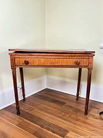 Front three-quarter view of closed gate leg table showing drawer and turned legs