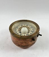 Oblique view of copper and brass compass showing glass top and patina
