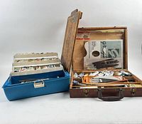 Blue tackle box and wooden case opened showing paint tubes and tools