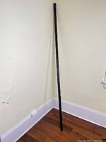 Full view of tall charred wood sculpture leaning in corner