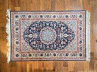 Full view of rectangular Persian Nain style rug on wood floor
