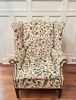 Front view of wingback chair showing crewel upholstery, seat cushion and mahogany legs