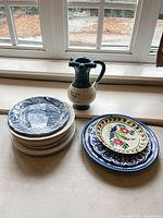 Stack of blue-white plates, two floral plates, puzzle jug