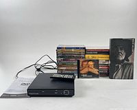 Front view Proscan DVD player, remote, cables, manual, stack of DVDs, two CDs