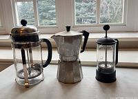 All three items side by side: Kuraidori french press, Gourmet Himark Kitchen moka pot, Pyrex french press