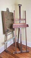 Two antique wooden easels side by side showing overall structure and patina