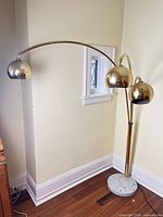 Full view of brass arc floor lamp with three arms and marble base