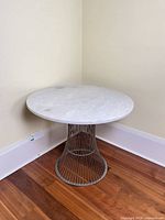 Full view of table against wall showing marble top and wire base