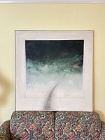 Framed abstract oil painting resting on sofa, full view with frame