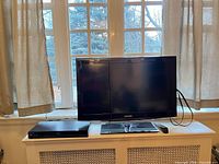 Front view of Samsung TV on stand with Blu-ray player and remote