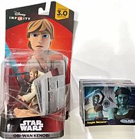 Obi-Wan Kenobi figure sealed in packaging beside stack of trading cards