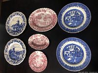 Seven decorative plates laid out: two windmill, two Willow, three Hunter