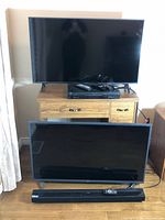 Two LG TVs, LG sound bar, JVC DVD player on stand