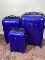 Front view of all three blue hard-shell spinner suitcases
