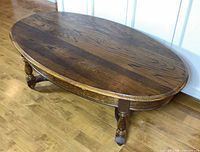 Three-quarter view of entire coffee table showing oval top, turned legs and stretcher